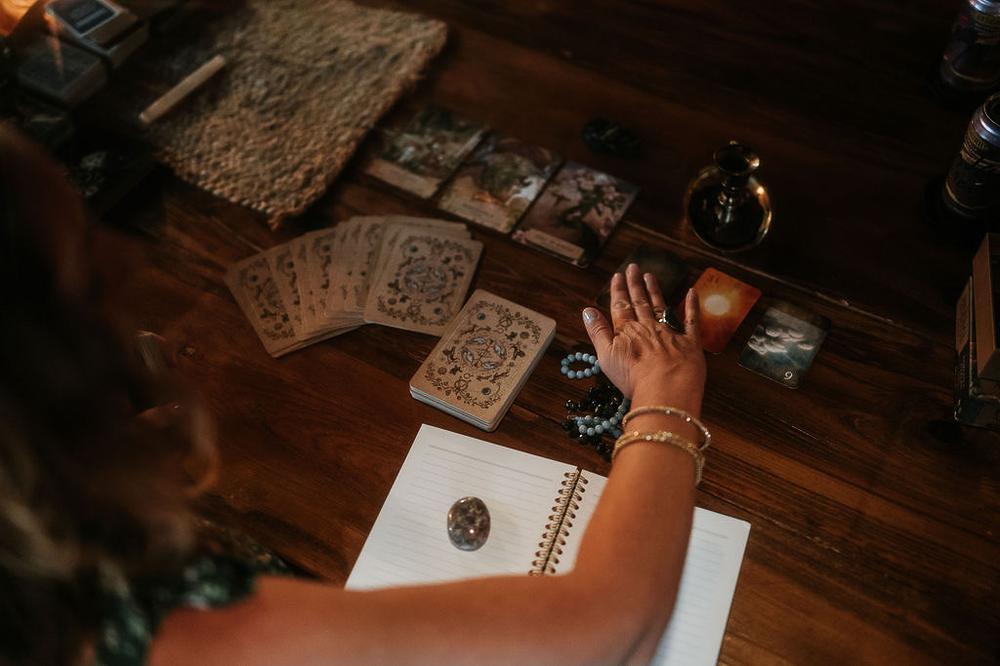 Holly's hands over a spread of oracle cards and a journal
